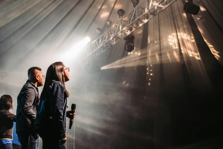 two people looking into the light while on stage