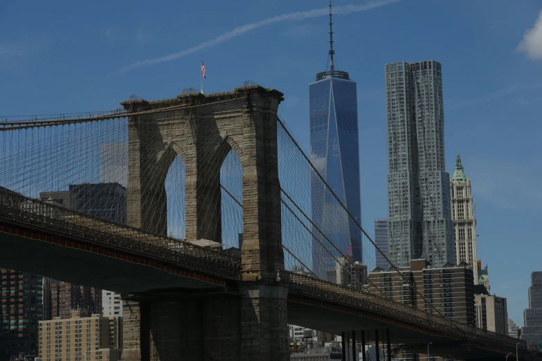 the view from the river, of a large bridge with a skyscr in the background