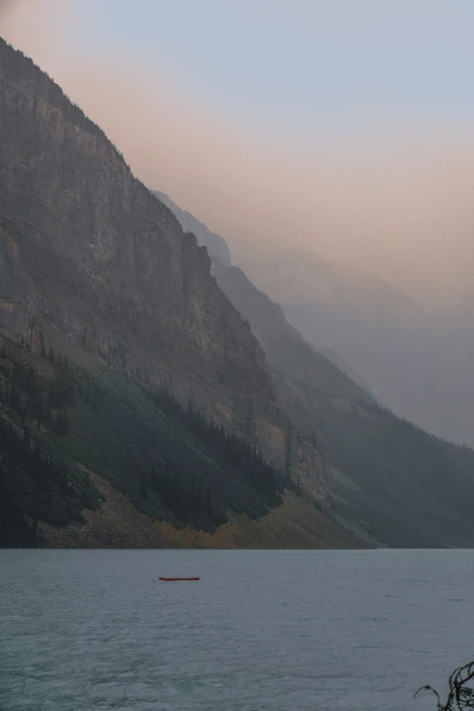 a boat floating on top of a lake with mountains in the background