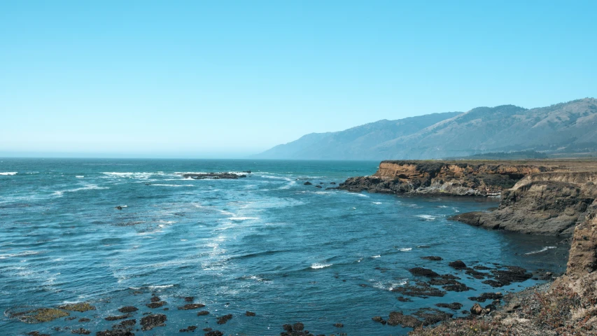 there are waves coming up in the sea near a cliff