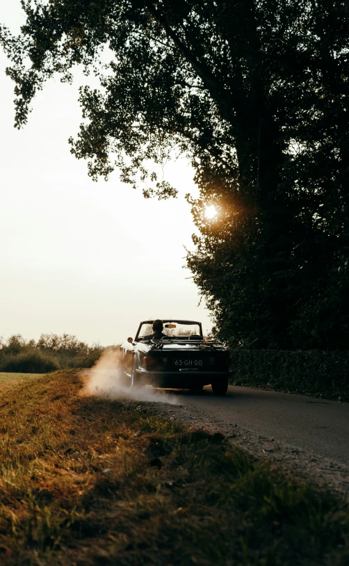 a jeep driving down a road with the sun in the background