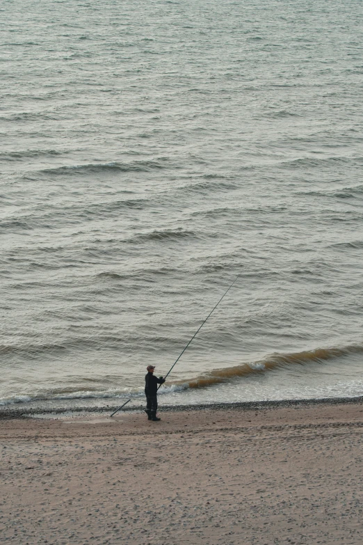 person fishing from shore near ocean with waves