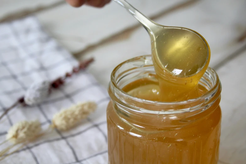 a spoon in a jar filled with honey