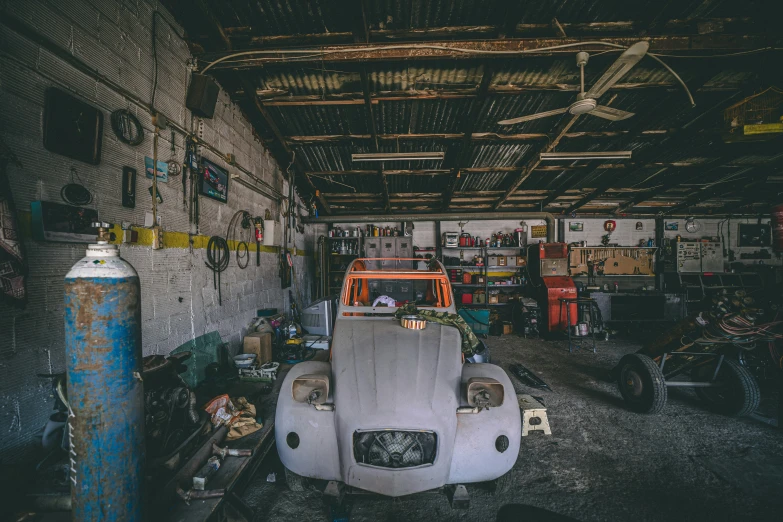 a car in a garage surrounded by various tools