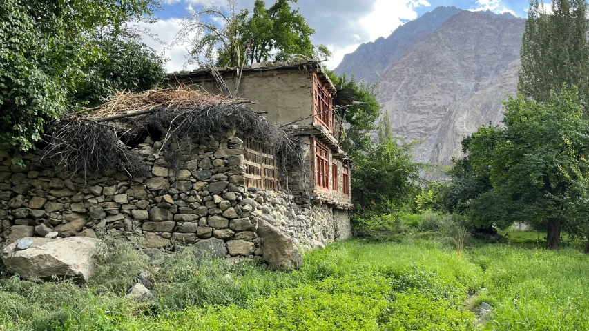 the house in the village is made of stone and is surrounded by lush grass