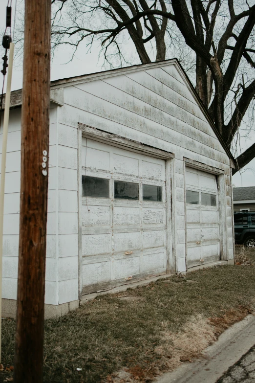 an old garage sits empty in front of trees