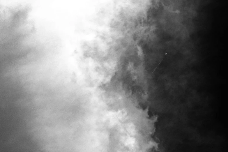 a single red plane flying in a cloudy sky