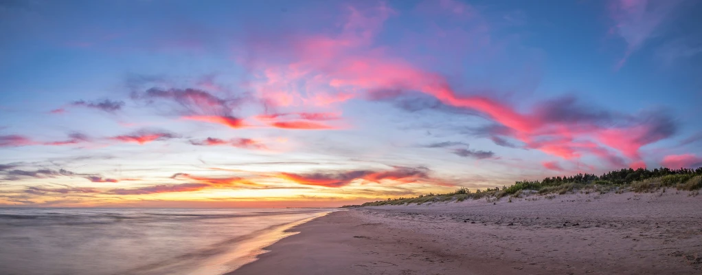 pink and orange clouds above the ocean near the beach