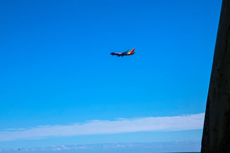 an airplane flying low over water by a large building