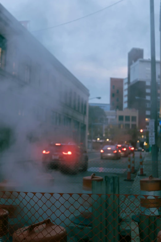 cars and trucks traveling down a road behind a chain link fence