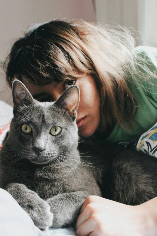 a woman laying on her bed with a gray cat