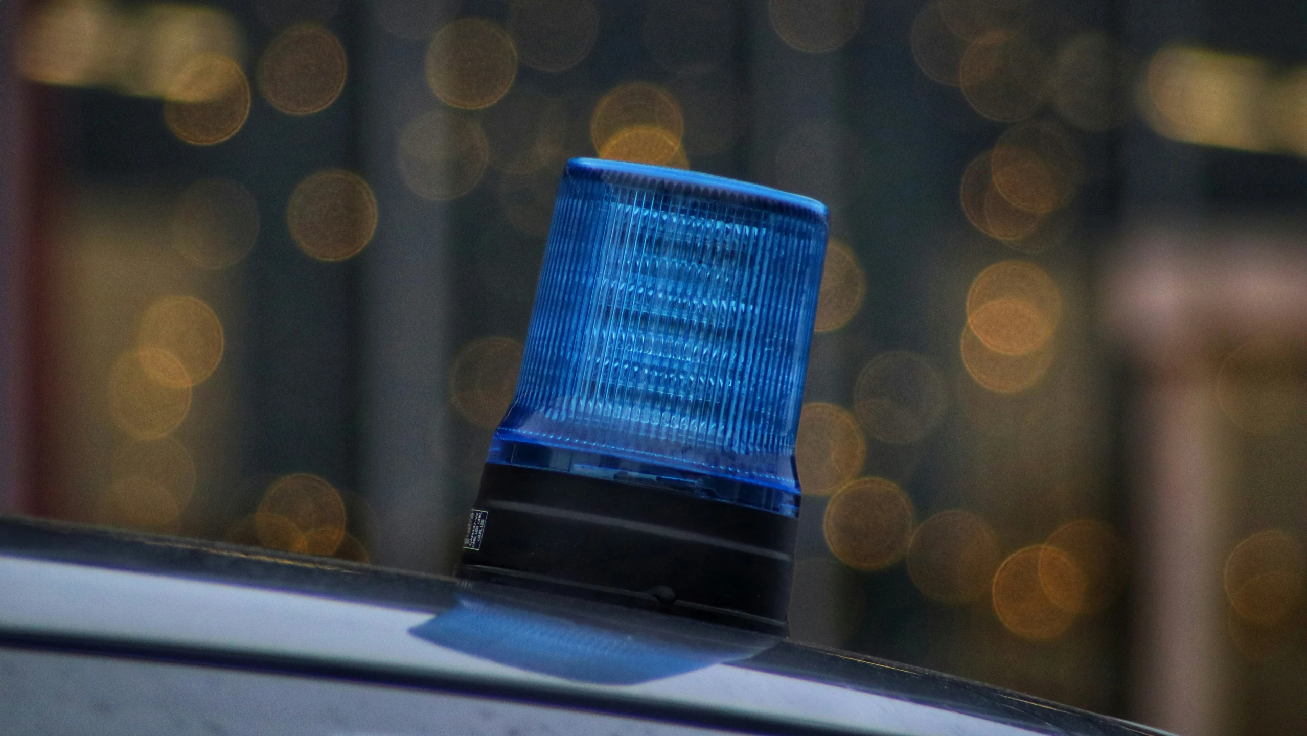 blue light on top of car with blurry city lights in background