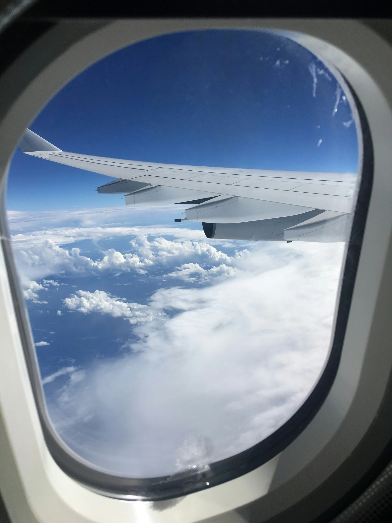 an airplane wing flying through the air above the clouds