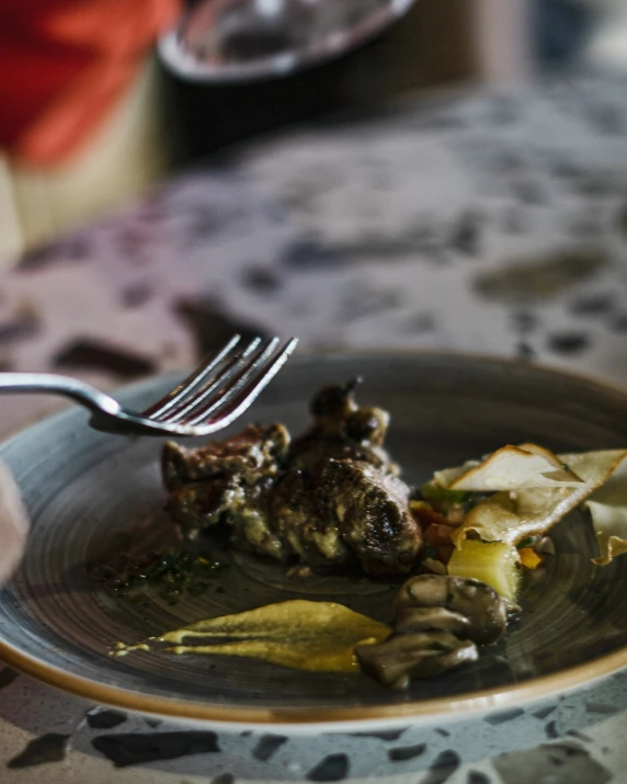 a piece of meat is on a plate with potatoes and mushrooms