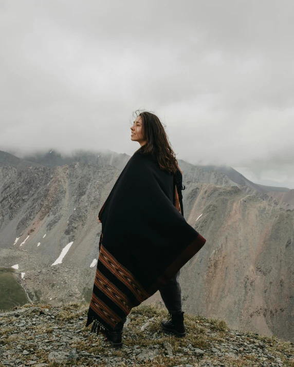 a woman standing on a mountain top in a blanket