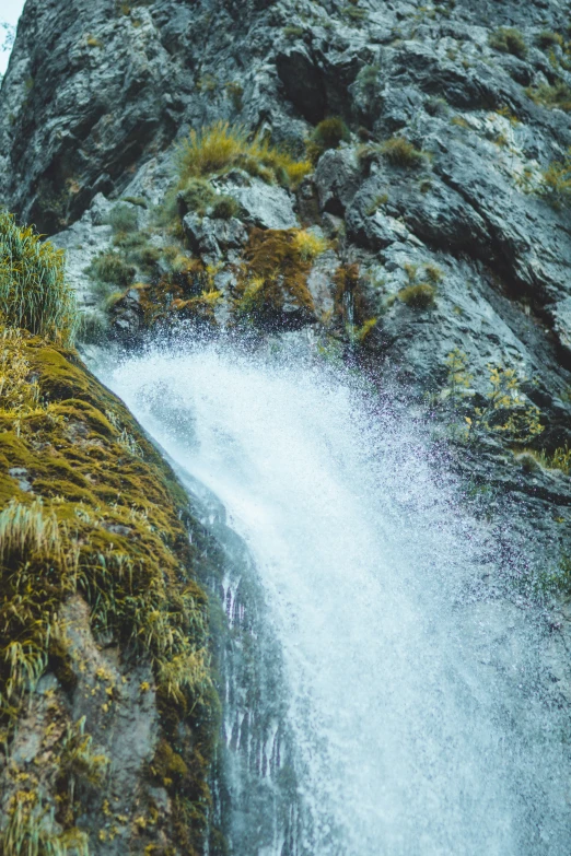 a very tall waterfall in the middle of some grass