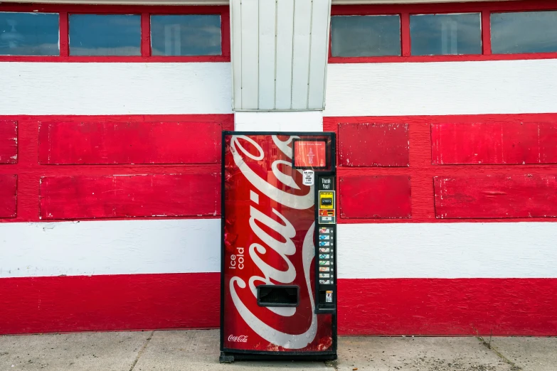 a soda vending machine sitting against a red and white painted wall