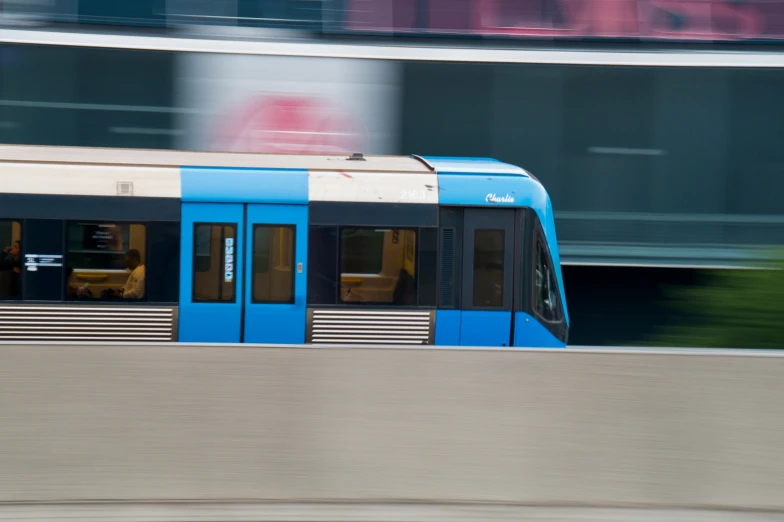 a blue train with a white stripe going down the track