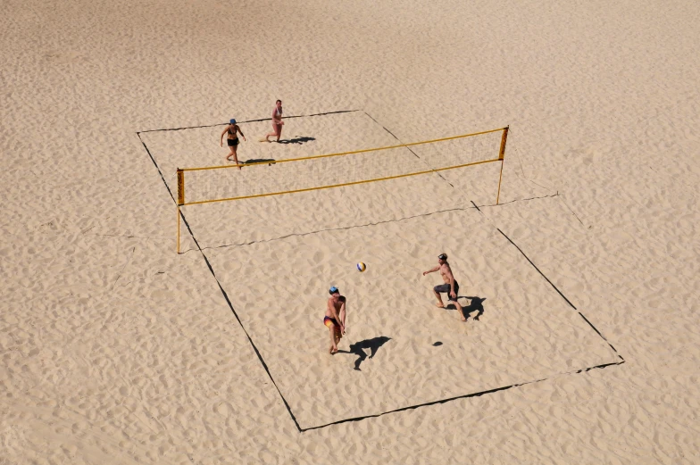 four people in the sand playing volleyball on a beach