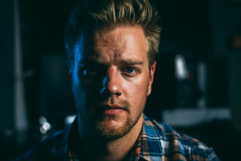 a young man in plaid shirt looking serious