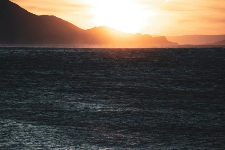 a boat sails on the ocean at sunset