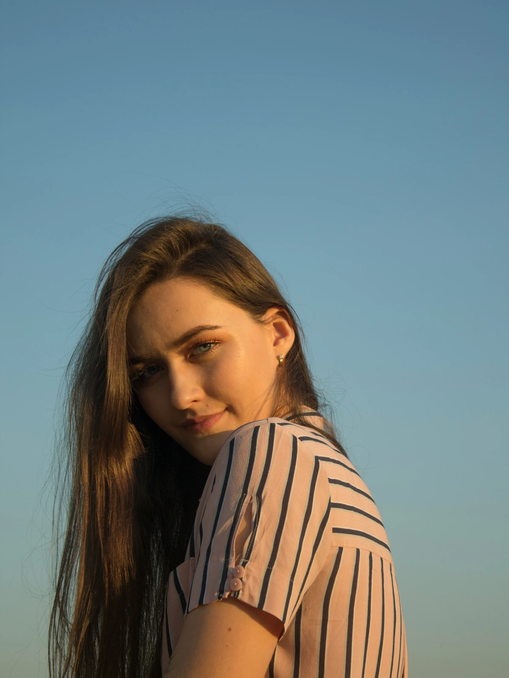 a woman posing in front of a sky