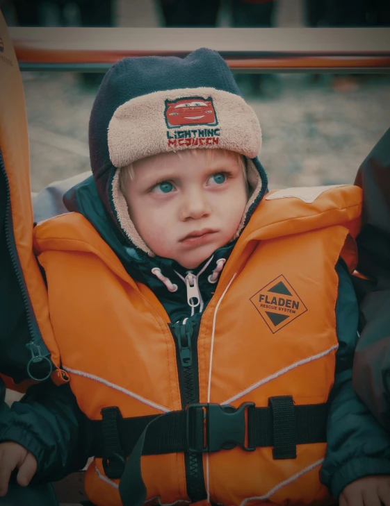  wearing an orange life jacket looking at the camera