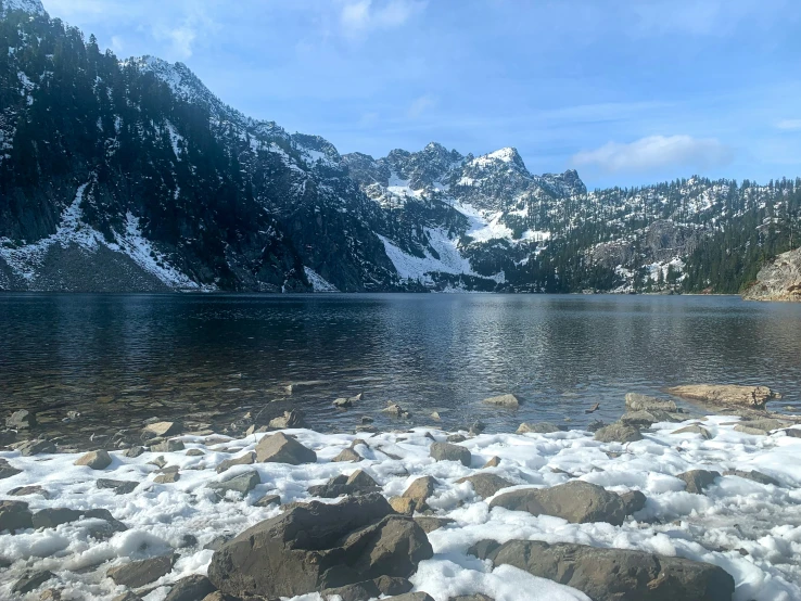 snow sits atop some rocks near a lake