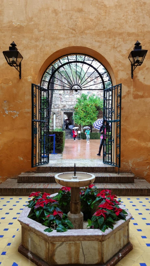 a courtyard with stone steps and a fountain with flowers