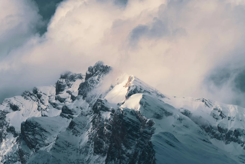 a tall snowy mountain covered in lots of clouds