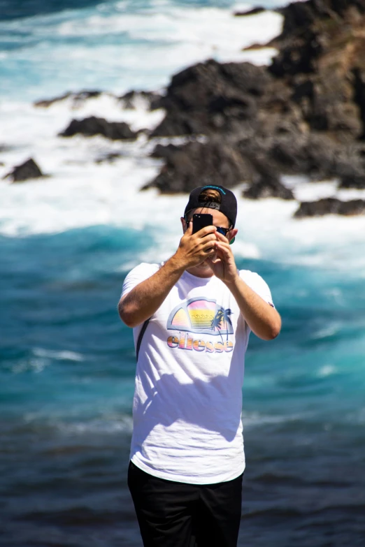 a person standing next to the ocean using a cell phone