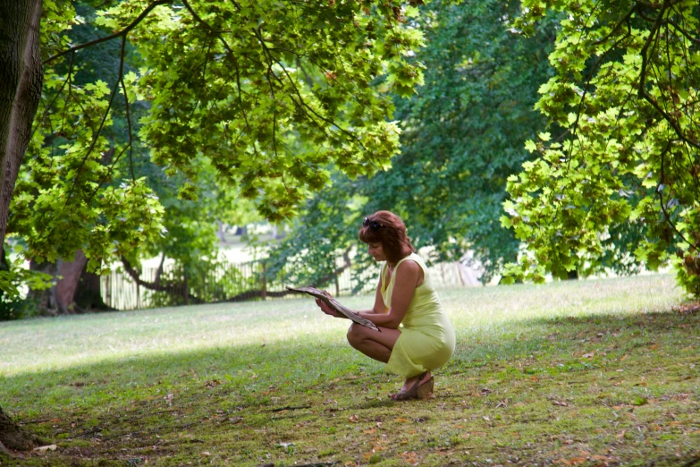 a young woman sitting on a green grass covered field