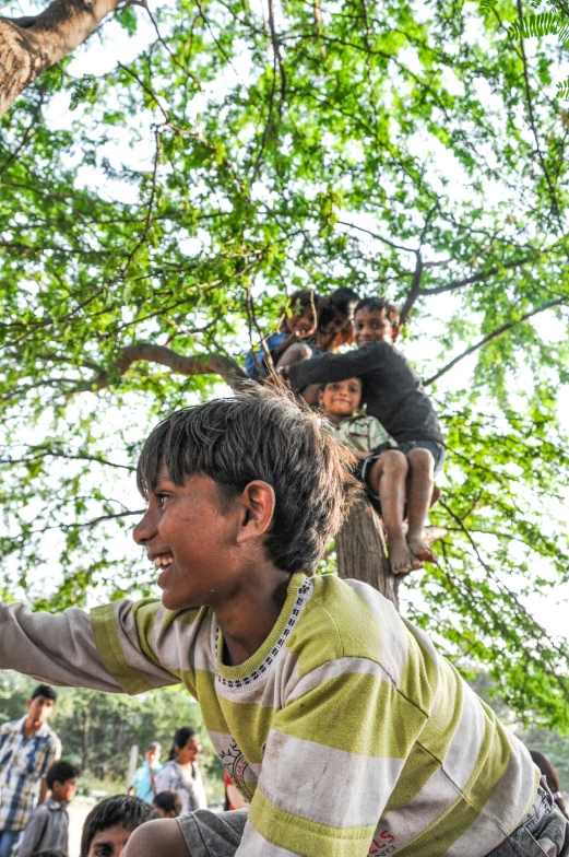 a woman in the air with her hands out while standing on her head in a tree, with people in the background