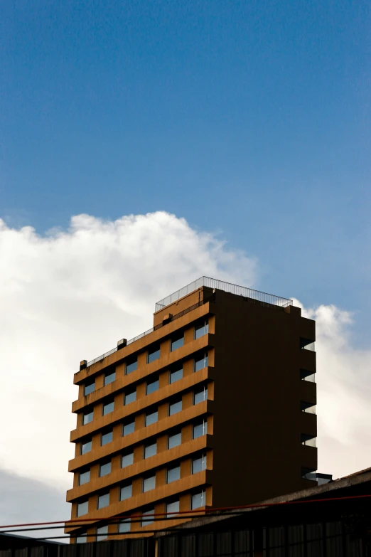 a red and brown building with blue sky and clouds