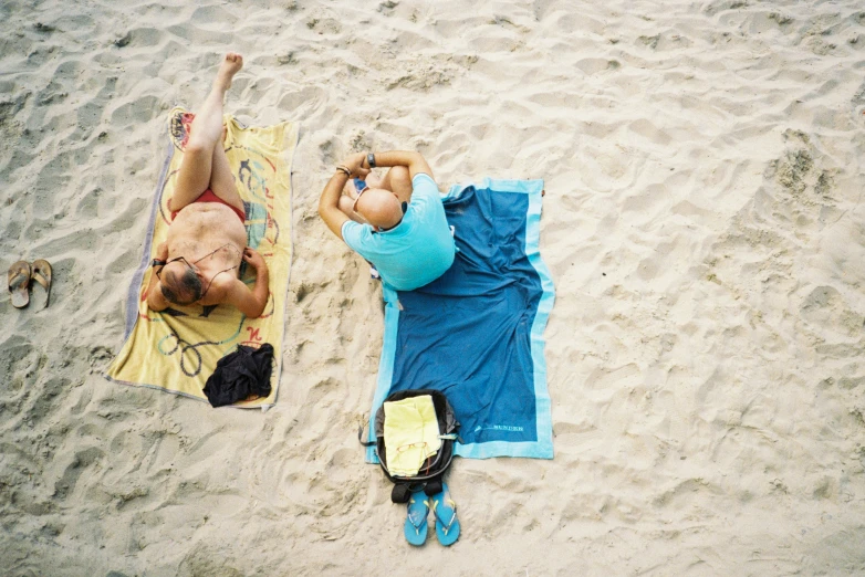 two people lay in the sand with towels and towels