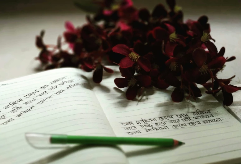 writing and a pencil are laying on a notebook with flowers