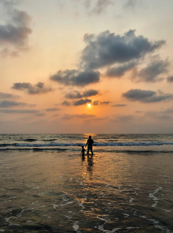 a man and a dog stand on the beach under a sunset