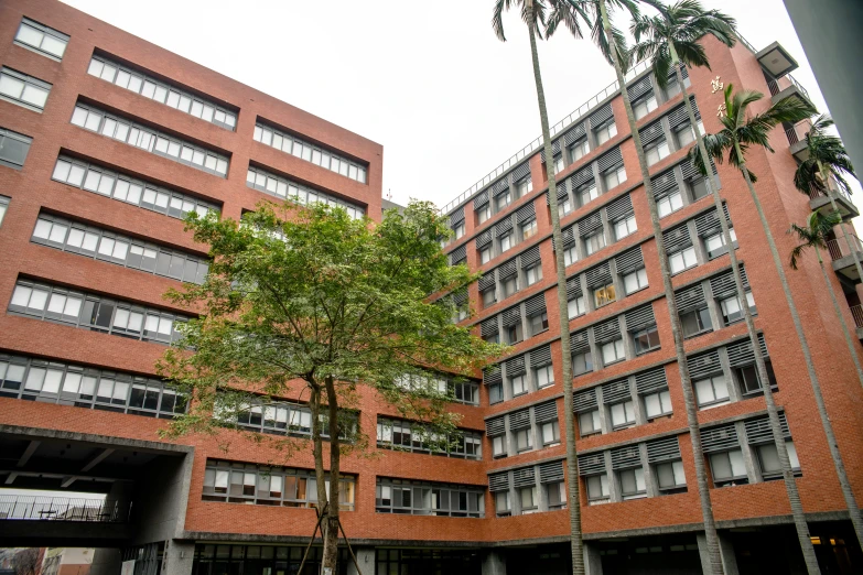 a tall red building with balconies next to trees