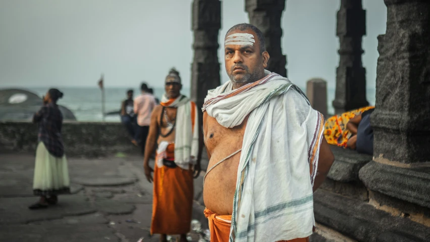 an old man with a towel wrapped around his neck standing outside