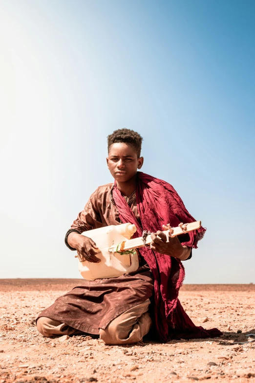 the man is playing his instrument outside on the ground