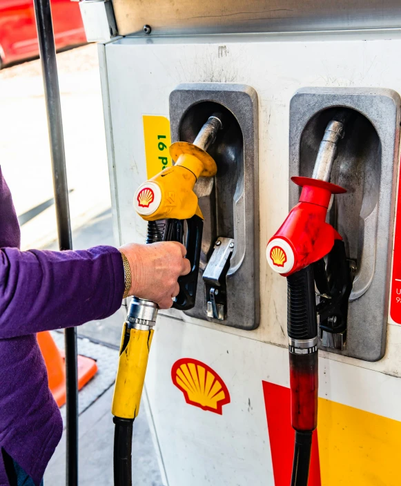 a woman fills the gas pump for her car at a gas station