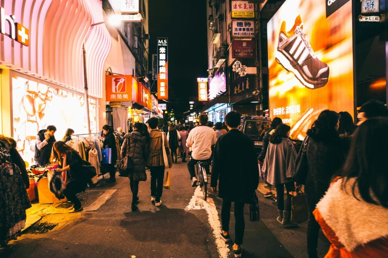 pedestrians walking down the street in a small asian city at night