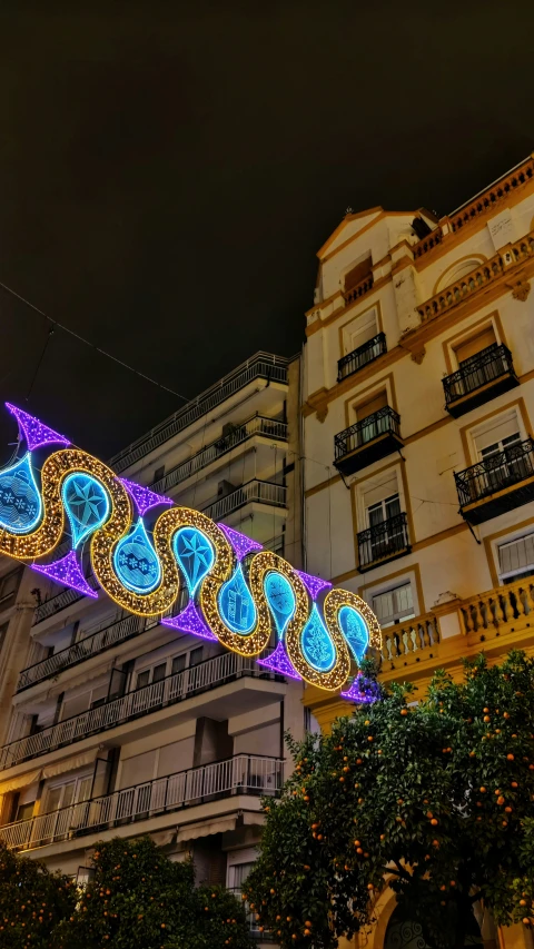 a long multi coloredly lighted banner next to buildings