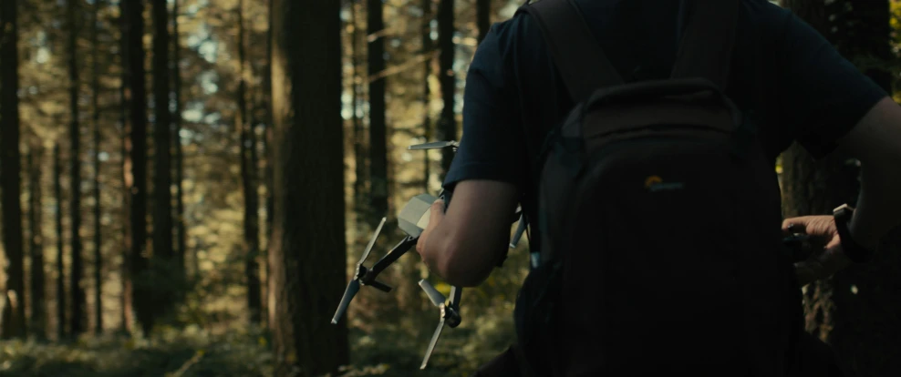 a man carrying some equipment in the woods