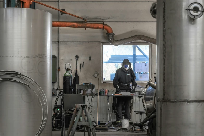 a man standing in a building next to stainless steel tanks