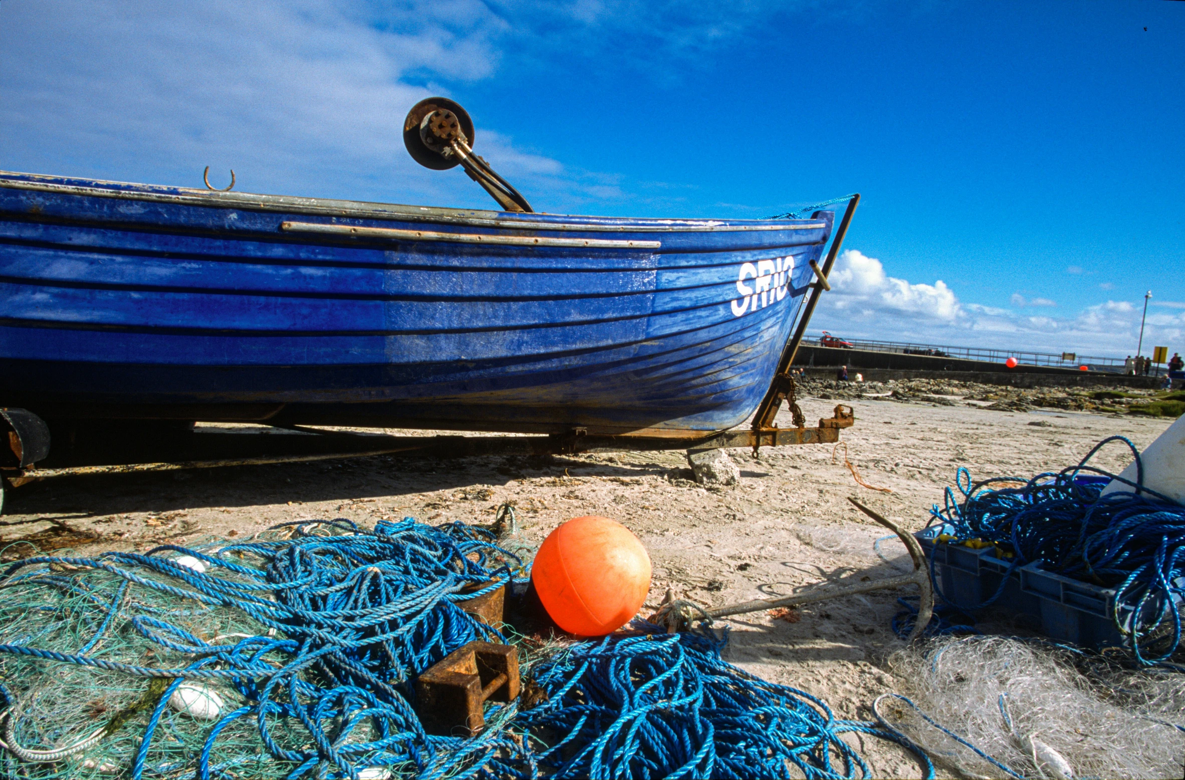 a boat on the sand next to a pile of blue ropes