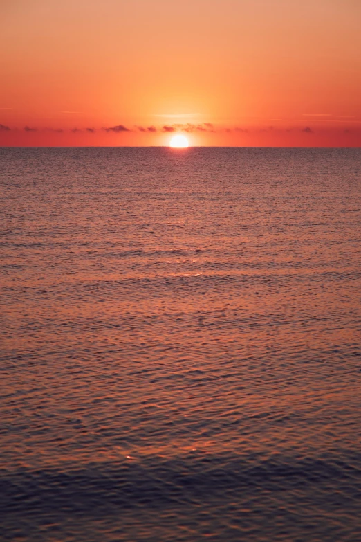 a sunset is seen behind a large body of water