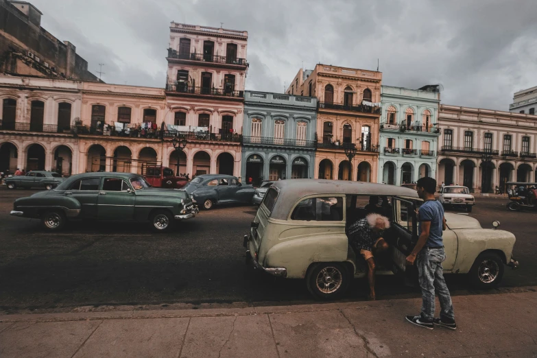 two men standing near an old car and cars on a road