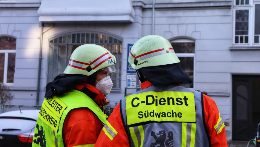 two people with yellow vests and masks on standing outside