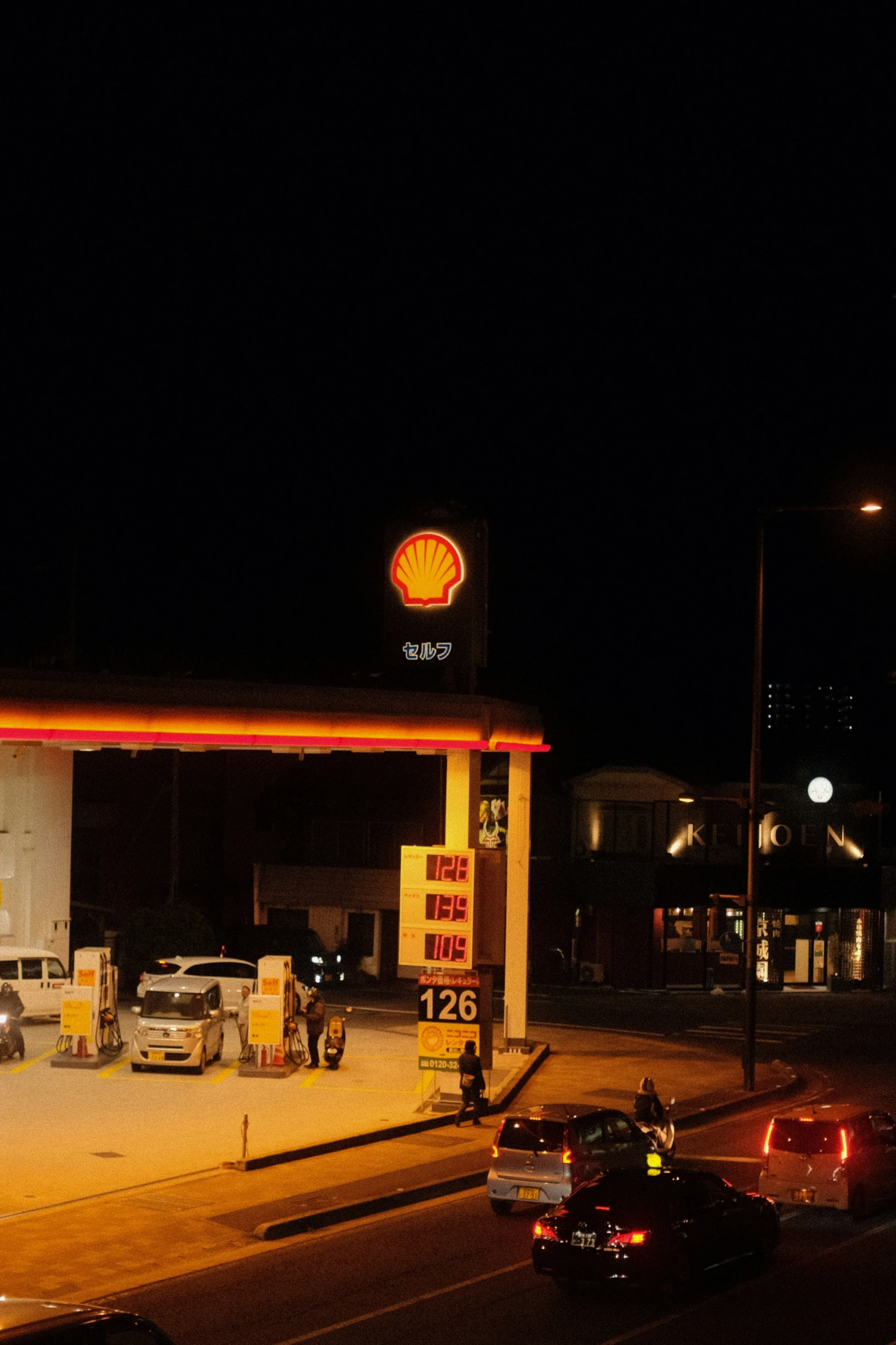 cars are parked at the gas station in the dark